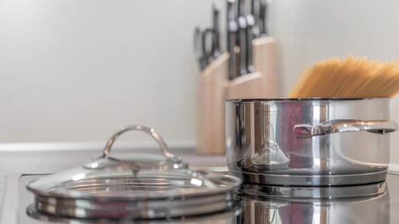 A pot of spaghetti on a stove. Sharp kitchen knives are visible in the background. - Ferienhaus Apart Sonnzeit - Sölden