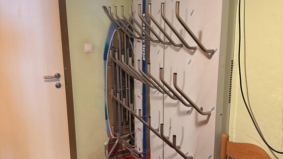A coat rack with several hooks stands against the wall. Next to it is a chair on a red carpet. - Ferienhaus Kaspers - Sölden