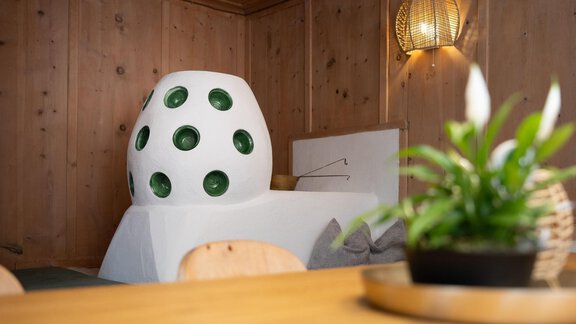 A cozy room with wood-paneled walls and a unique egg-shaped sofa. A small plant sits on the table, adding fresh greenery. - Ferienhaus Valsora - Sölden