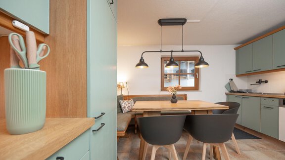 A modern kitchen with mint green cabinets and a wooden dining area. The room is bright and friendly with an inviting atmosphere. - Ferienhaus Valsora - Sölden