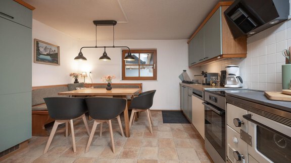 A modern kitchen with a dining table and chairs. The walls are in soft colors, and there is a cozy atmosphere. - Ferienhaus Valsora - Sölden
