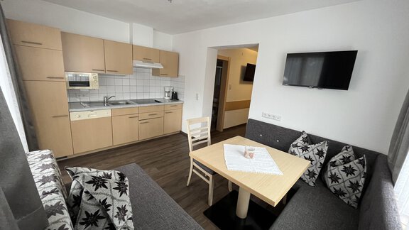 A modern apartment with a well-equipped kitchenette and a spacious dining area. The furniture is comfortable and inviting, ideal for a relaxing stay. - Franzele Appartements & Zimmer - Sölden