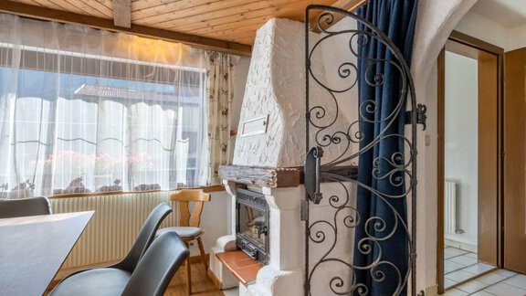 A cozy room with a fireplace and a wooden table. The windows let in a lot of light and the decoration is inviting. - Garni Nadine - Sölden