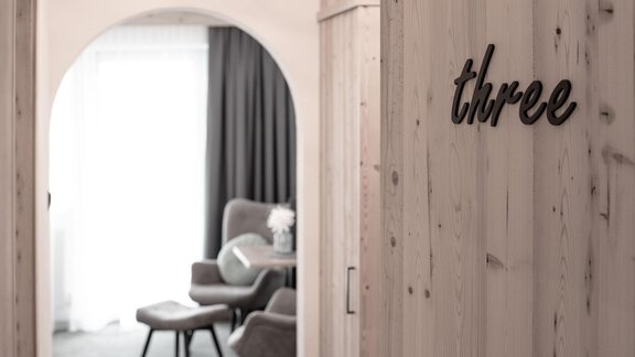 A stylish room with modern furniture and a warm, inviting ambiance. The inscription "three" is clearly visible on the wall. - Garni Rustica - Sölden