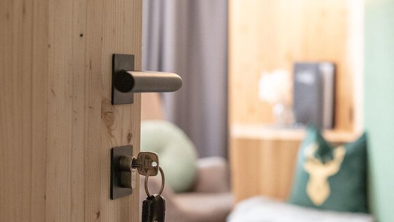 A half-open door to a modern, cozy room. In the background, wood and a comfortable seating area can be seen. - Garni Rustica - Sölden