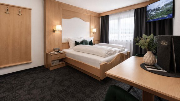 A modern hotel room with two beds and a desk. It has large windows and a cozy atmosphere. - Garni Rustica - Sölden