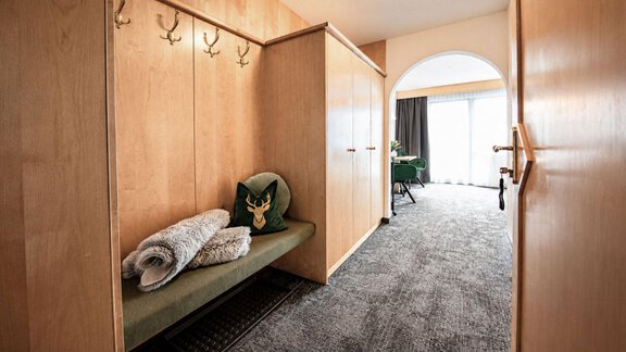 A modern hallway with wooden paneling and a bench. Towels are laid on the bench and in the background, a public area with a balcony is visible. - Garni Rustica - Sölden