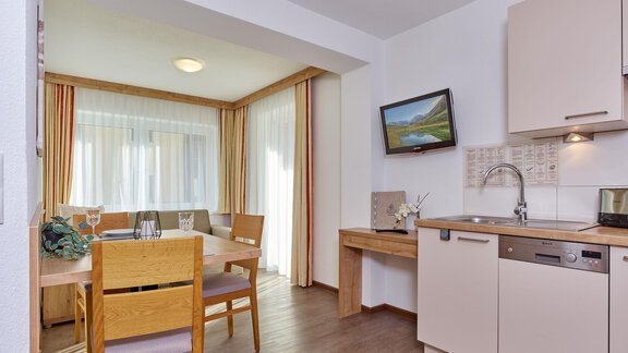 A cozy kitchenette with a dining table and chairs. Large windows provide plenty of light and a welcoming atmosphere. - Gästehaus Bergkristall - Sölden