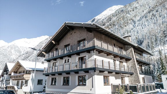 A modern building in the snow, surrounded by mountains. The sky is clear and the landscape looks wintry and inviting. - Gästehaus Dr. Riml - Sölden
