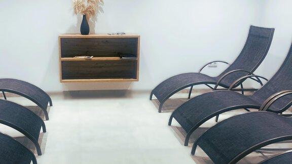 A quiet relaxation room with modern loungers. In the background stands an elegant sideboard with decorative elements. - Gästehaus Europa - Sölden