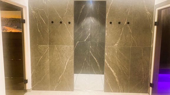 A modern space with gray marble panels and elegant lighting. The walls are designed in a minimalist style and convey a simple elegance. - Gästehaus Europa - Sölden