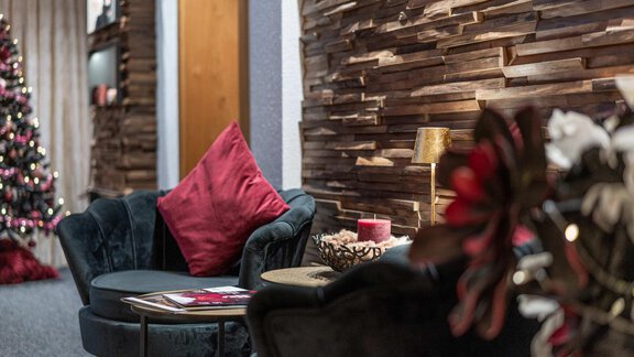 A stylish living space with a cozy couch and a round table. In the background, there is a decorated Christmas tree. - Gästehaus Maier - Sölden