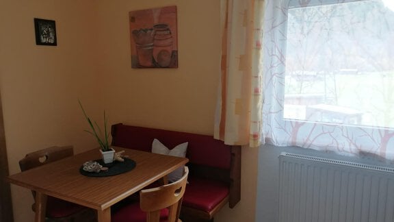 A cozy dining area with a wooden table and chairs. Pictures hang on the wall, and a window lets in plenty of light. - Gästehaus Sternberger - Sölden
