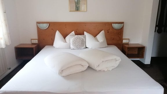 A cozy bedroom with a large bed and bright, modern furniture. The atmosphere is warm and inviting, perfect for relaxing. - Gästehaus Sternberger - Sölden
