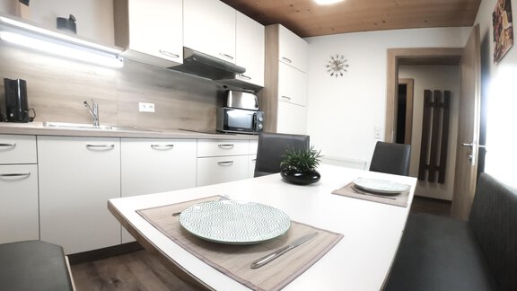 A modern kitchen with a dining table and chairs. The walls are light, and the room is well-lit. - Gästeheim Schmiedhof - Sölden