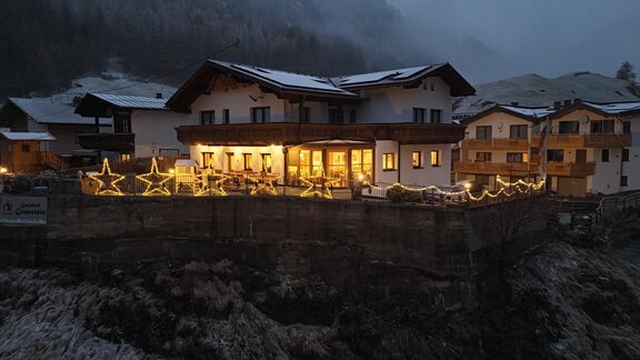 A charming mountain cabin with warm light and festive decorations. The snow-covered background conveys a cozy winter atmosphere. - Gasthof Granstein - Sölden
