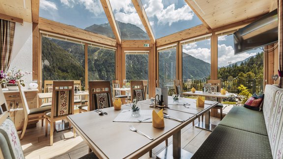 A bright restaurant with large windows and a view of the mountains. Tables are prepared for guests, and a cozy atmosphere is noticeable. - Gasthof Granstein - Sölden