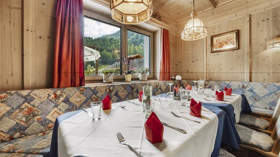 A beautifully set table in a cozy restaurant with wood paneling. Red napkins and glasses complement the inviting atmosphere. - Gasthof Granstein - Sölden