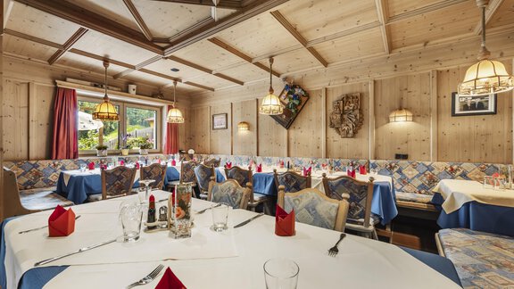 An inviting restaurant with wooden walls and set tables. The atmosphere is cozy, with red napkins and warm lighting. - Gasthof Granstein - Sölden