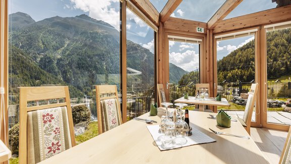 A bright and cozy restaurant environment with large windows and a view of the mountains. The table is set for guests, surrounded by an inviting atmosphere. - Gasthof Granstein - Sölden