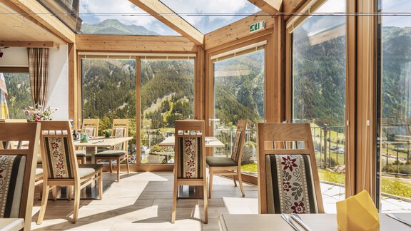 A light-filled restaurant with large windows and a view of the mountains. The tables are comfortably furnished and invite you to linger. - Gasthof Granstein - Sölden