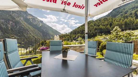 A beautiful outdoor area with a view of the mountains. The table is neatly set and surrounded by chairs. - Gasthof Granstein - Sölden
