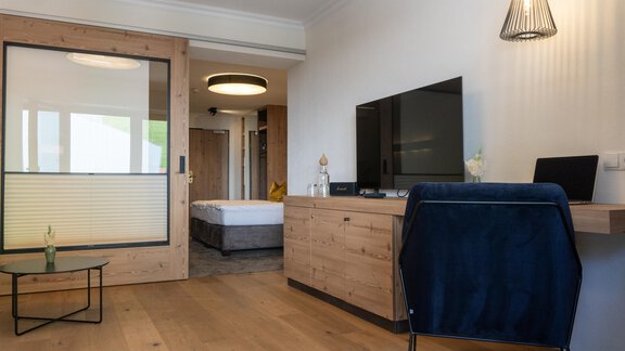 Ein modernes Zimmer mit Holzfurnier und einem großen Fernseher. Die Einrichtung ist schlicht und gemütlich, ideal für Entspannung. - Glanz & Glory Hotel - Sölden