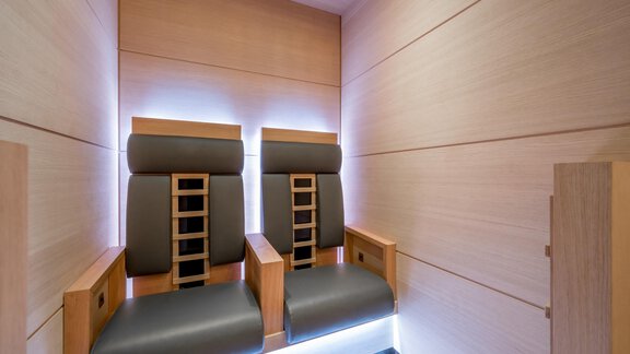 A quiet wellness area with two modern loungers. The walls are made of light wood, and there is soft indirect lighting. - GREEN.Apartments by Camping Sölden - Sölden