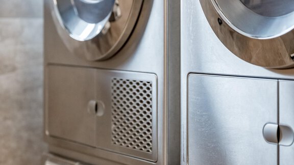 A modern laundry room with two silver Miele washing machines. The machines are arranged side by side and have large transparent doors. - GREEN.Apartments by Camping Sölden - Sölden