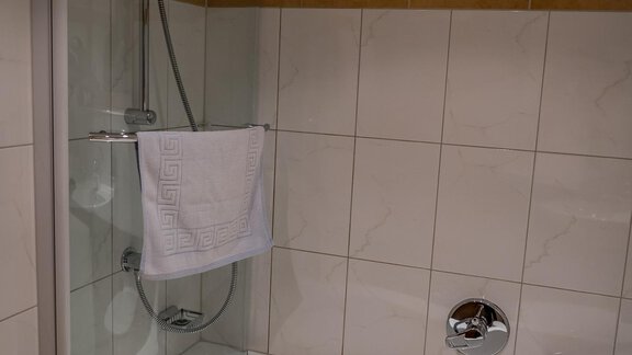 A modern bathroom with a bathtube and a shower cabin. The walls are equipped with bright tiles. - Haus Almrausch - Sölden