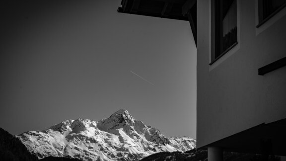 A snow-covered mountain is visible in the background, while part of a house is visible in the foreground. The sky is clear and the scene conveys a calm atmosphere. - Haus Almrausch - Sölden