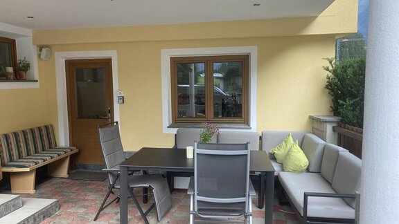 A cozy terrace with modern furniture and a comfortable seating area. The walls are painted in light yellow and there is plenty of natural light. - Haus Almrausch - Sölden