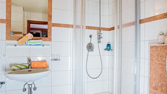 A modern bathroom with a shower cabin and bright tiles. Towels and toiletries are neatly arranged. - Haus Alois - Sölden