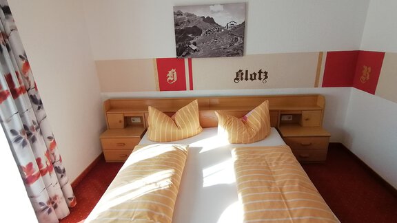 A cozy bedroom with two single beds and yellow bed covers. The walls are painted in soft colors, with a picture above the bed. - Haus Alt Schmiedhof - Sölden