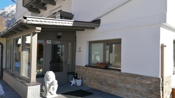 A modern building with an inviting entrance. In front of the door stands a decorative lion figure. - Haus Alt Schmiedhof - Sölden