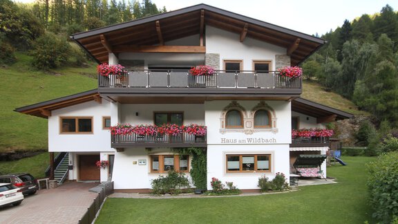 A beautiful house with a balcony and colorful flowers. It is situated surrounded by green nature. - Haus am Wildbach - Sölden