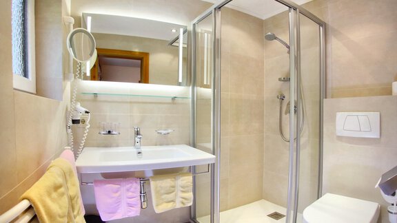 A modern bathroom with a shower, sink, and toilet. Bright tiles and practical towels create an inviting atmosphere. - Haus am Wildbach - Sölden