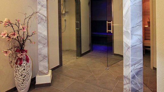 A stylish entrance area with columns and an elegant flower arrangement. The space feels modern and inviting. - Haus am Wildbach - Sölden
