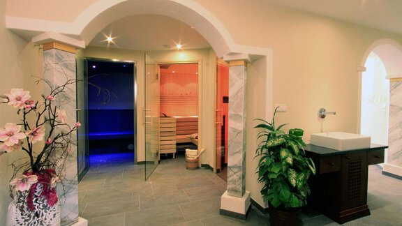 An elegant wellness area with two saunas in different colors.  
Green plants and decorative flowers create a relaxing atmosphere. - Haus am Wildbach - Sölden