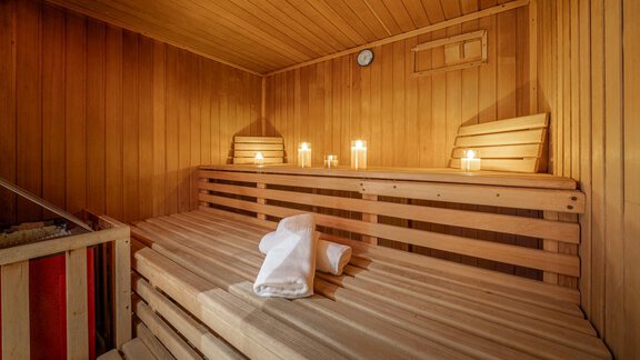 A cozy sauna with wooden shelves and soft lighting. Two towels are laid out on the bench, ready for use. - Haus Amaris - Sölden