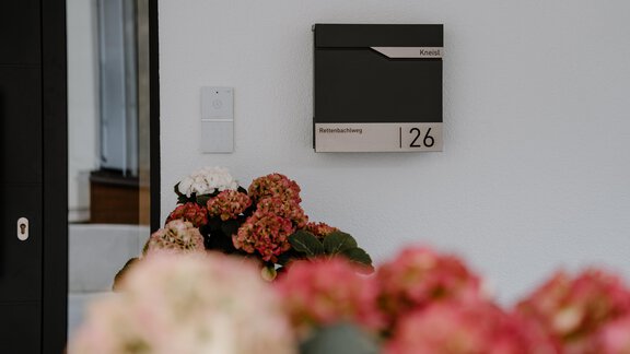 A mailbox with the number 126 on a wall. In the foreground, colorful flowers can be seen. - Haus Crystal - Sölden