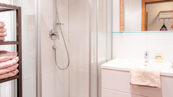 A modern bathroom with a shower cabin and a sink. The wooden floor and towels create a cozy atmosphere. - Haus Edmund - Sölden