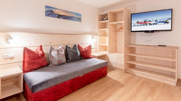 A modern room with a cozy sofa and wooden furniture. A flat-screen TV and a large window provide brightness. - Haus Edmund - Sölden