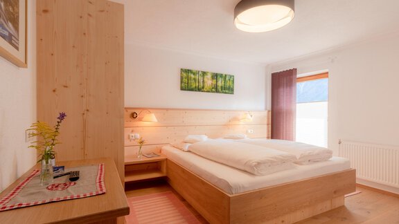 A cozy bedroom with wood decor and a large double bed. Bathed in light with a window and beautiful wall decoration. - Haus Edmund - Sölden