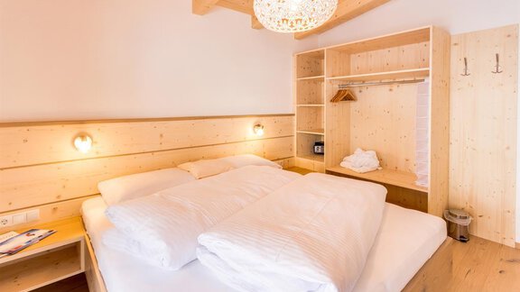 A cozy bedroom with wooden paneling and a large double bed. The quiet atmosphere is enhanced by the warm light sources and the simple furnishings. - Haus Edmund - Sölden