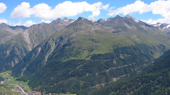 An impressive mountain landscape with high peaks and green valleys. The sky is clear and blue, highlighting the natural beauty. - Haus Erwin - Sölden