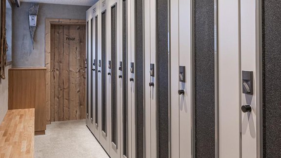 A modern hallway with several cabinets on both sides. The floor is covered with carpet and the ceiling has an interesting pattern. - Haus Manfred - Sölden