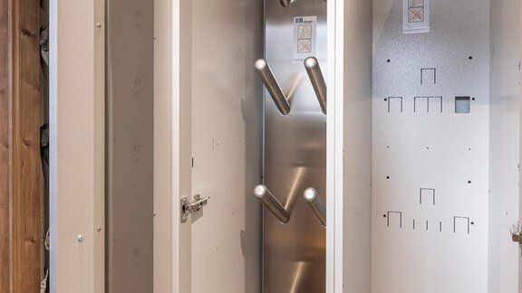 A modern, narrow wardrobe with a metal suspension for garments. The interior is simply and brightly designed. - Haus Manfred - Sölden