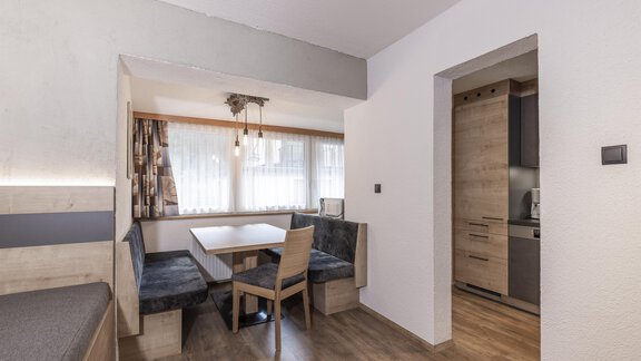A modern living room with a cozy seating area and a table. The bright walls and the wood veneer create an inviting atmosphere. - Haus Manfred - Sölden