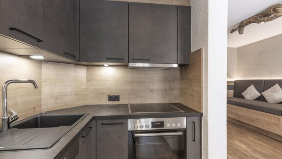 Modern kitchen with dark cabinets and stainless steel appliances. The room has a bright, warm atmosphere. - Haus Manfred - Sölden